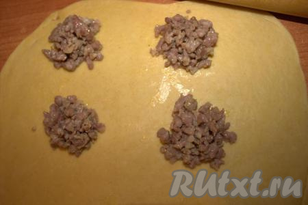 Одну часть теста прикрыть пищевой плёнкой (чтобы не заветрилось). Вторую часть теста раскатать скалкой в прямоугольник толщиной 1 мм. Чайной ложкой на тесто выложить обжаренный и остывший фарш на расстоянии, примерно, 3-4 сантиметра друг от друга.