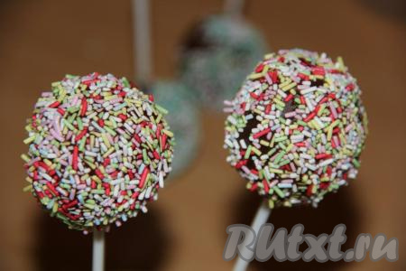 Достать шарики на палочке из морозилки и покрыть их растопленным шоколадом, сразу посыпать кондитерской посыпкой. Так как пирожные холодные, шоколад быстро схватывается. Оставить кейк-попсы на подставке (или в стакане), чтобы шоколад полностью застыл.