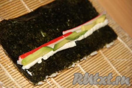 Авокадо разрезать пополам, удалить косточку и очистить. Нарезать авокадо на брусочки. Выложить авокадо на творожный сыр.