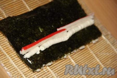 Рядом с творожным сыром выложить крабовую палочку, разрезанную пополам.