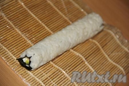 Начиная с края, ближе к которому выложен творожный сыр, свернуть с помощью циновки плотный ролл&nbsp;(слой риса у нас окажется снаружи).