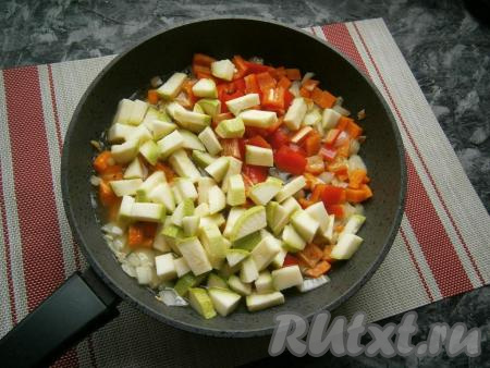 Лук с морковью выложить на разогретую с растительным маслом сковороду и, помешивая, обжарить их в течение 2-3 минут на небольшом огне. Затем&nbsp;добавить в сковороду кабачок и болгарский перец, влить горячую воду, посолить, перемешать.