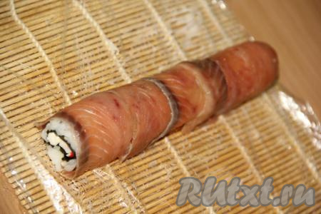 Тонкие ломтики красной рыбы выложить поверх риса.