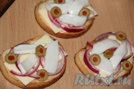 Оливки нарезать тонкими кружочками и выложить на бутерброды.