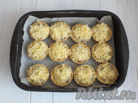 Сверху начинку посыпьте натёртым сыром. Поставьте тарталетки с грибным жульеном в разогретую духовку на 3-4 минуты.