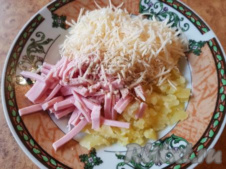 Мякоть, которую достали из половинок картофеля, нарезать на небольшие кусочки, добавить нарезанную колбасу и натёртый сыр, посолить и поперчить по вкусу.