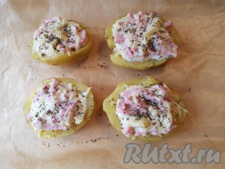 Половинки картофеля, фаршированные колбасой и сыром, переложить на противень,&nbsp;застеленный пергаментом (смазать сливочным или подсолнечным маслом места на пергаменте, куда будете выкладывать фаршированные половинки). Сверху посыпать сушёным базиликом. Запекать картофель в разогретой до 200 градусов духовке минут 10-15.