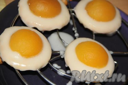 Печенье выложить на решётку, каждую печенюшку полить 1-2 чайными ложками глазури. Равномерно распределить глазурь по поверхности печенья. Глазурь должна стекать и закрыть бока печенюшек. На каждое печенье поверх глазури выложить дольку консервированного абрикоса и оставить до полного застывания глазури (примерно, на 1 час).