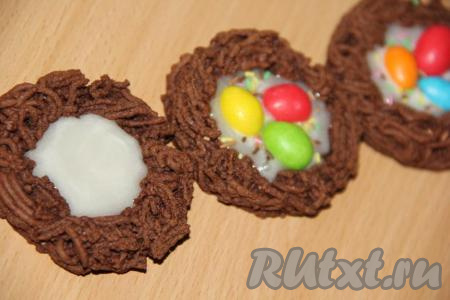 В каждое остывшее пасхальное печенье "Гнездо" влить немного глазури и сразу выложить цветные конфетки овальной формы, можно украсить кондитерской посыпкой.