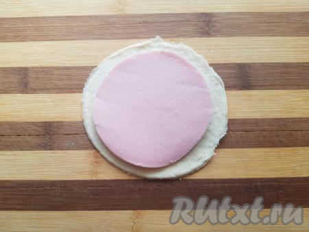 Далее начинаем формировать булочки. Для формирования каждой булочки понадобится 3 кружочка из дрожжевого теста и 2 кусочка колбасы (кружочек теста должен быть больше по размеру кусочка колбасы). На кружочек теста положить кусочек колбасы.