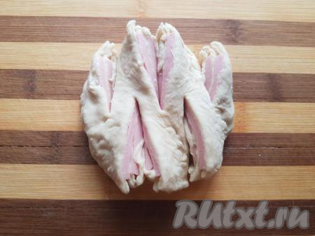 Далее развернуть кусочки булочки срезами вверх так, чтобы была видна колбаска (как показано на фото). Аналогично сформировать все булочки с колбасой из дрожжевого теста (у меня получилось 8 штук).