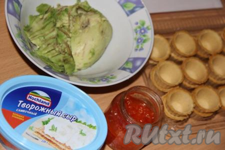 Подготовить продукты для приготовления тарталеток с авокадо и творожным сыром. Авокадо должен быть мягким. Разрезать авокадо на две части и удалить косточку. С помощью ложки достать мякоть авокадо и выложить на тарелку.