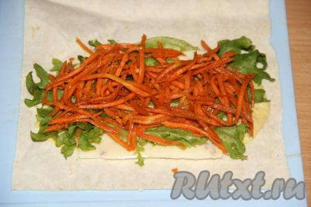 Поверх листьев салата выложить корейскую морковь.