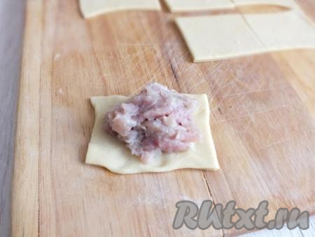 Возьмите квадратную заготовку теста и выложите неполную столовую ложку фарша.