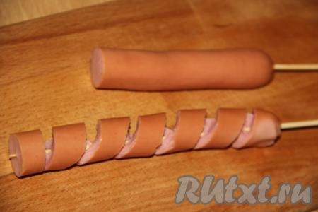 Я взяла 6 венских сосисок, затем каждую сосиску разрезала&nbsp;на 2 части (обычные сосиски разрезать пополам не нужно). Нанизать сосиску (я нанизывала половину сосиски) на длинную шпажку и разрезать острым ножом сосиску по спирали (как на фото), поворачивая шпажку. Аккуратно растянуть сосиску. Аналогично надеть все половины сосисок на шпажки и надрезать в виде спиралей.