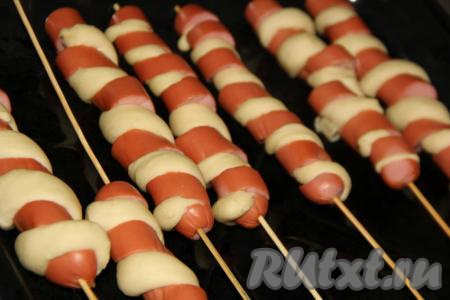 Шпажки с сосисками и тестом выложить на противень, смазанный растительным маслом, и оставить минут на 30-40 для расстойки.