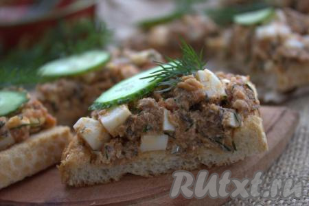 Огурец вымыть и нарезать на тонкие кружочки. Украсить каждый бутерброд с килькой в томате кружочком огурца и веточкой укропа.