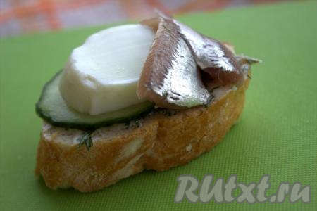 По 2 подготовленных кильки выложить&nbsp;на каждый ломтик&nbsp;хлеба с маслом (я свернула рыбку цветочком). Рядом с килькой положить по кружочку огурца и яйца.