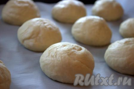 Далее подошедшее тесто обмять руками и разделить на 9-10 равных частей (весом, примерно, по 100-120 грамм). Каждую часть теста сформировать в шар. Пергаментной бумагой застелить противень (или смазать противень растительным маслом), выложить на противень заготовки из теста на расстоянии друг от друга.