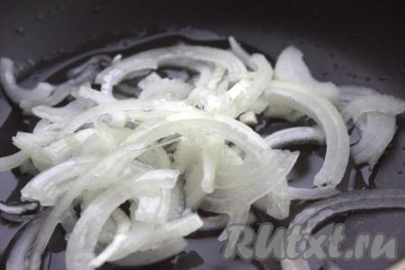Почистить лук, нарезать тонкими полукольцами и выложить в разогретую сковороду с добавлением растительного масла. Обжарить лук в течение 2-3 минут, помешивая, на среднем огне.