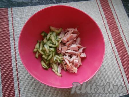 В миску выложить кусочки копчёной курицы, добавить свежий огурчик, нарезанный соломкой.