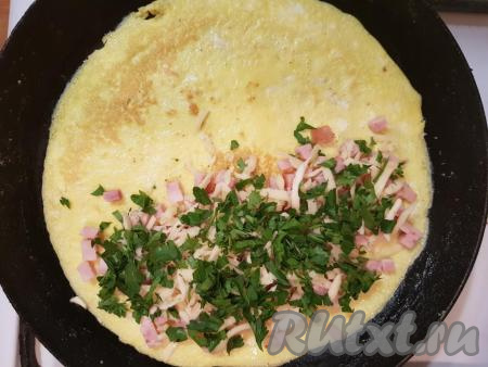 Далее выложить яичницу на сковороду (лаваш должен быть снизу). На половине яичницы равномерно распределить нарезанную небольшими кубиками колбасу, натёртый сыр и мелко нарезанную петрушку.