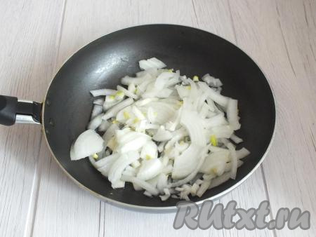 Пока остывают кальмары, очистите лук и нарежьте на четверть кольца. В сковороде разогрейте 3 столовые ложки растительного масла и опустите в него подготовленный лук. На среднем огне обжарьте лук, иногда помешивая, до лёгкой золотистой корочки (это займёт 7-10 минут).