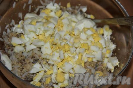 В салат из риса и консервированной скумбрии добавить яйца.