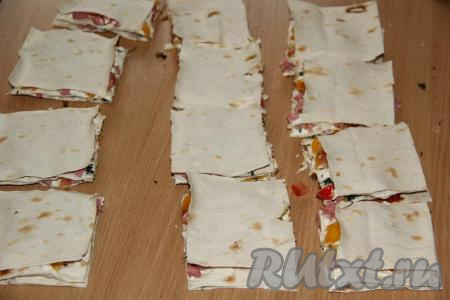 Разрезать лаваш с начинкой на квадратики размером, примерно, 8х8 см.