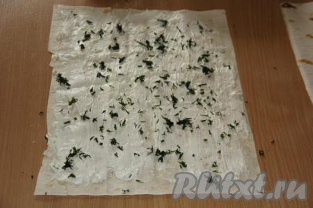 Вымыть, обсушить и мелко нарезать зелень. Половиной нарезанной зелени присыпать смазанную часть лаваша.