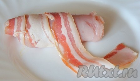 Каждый кусочек куриной грудки, свернутой в рулет, обернуть полосками бекона.
