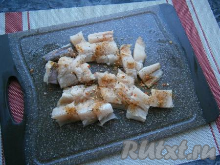 Филе хека нарезать на небольшие кусочки, посыпать приправой и посолить.