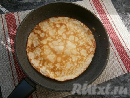 Пока начинка остывает, нужно пожарить блинчики, для этого на разогретую сковороду, смазанную растительным маслом (смазывать сковородку нужно перед жаркой только первого блина), вылить порцию теста, равномерно распределить и жарить блин с двух сторон до румяности на среднем огне, а затем переложить на тарелку. Пожарить таким образом все блины, складывая их на тарелку стопочкой.