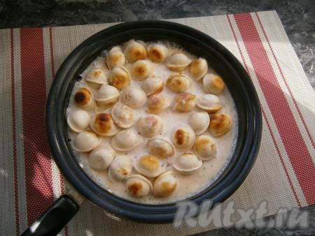 Когда пельмени поджарятся, влить в сковороду сметанную смесь.