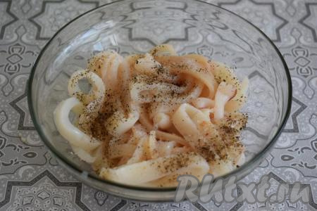 Нарезанных кальмаров обсушиваем при помощи бумажных полотенец, складываем в миску, солим и перчим по вкусу.