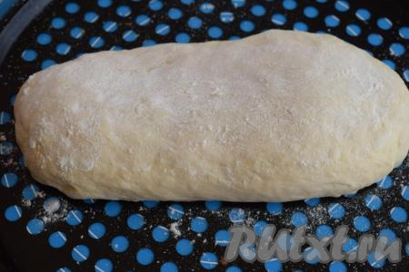 Получившуюся улитку снова растягиваем в пласт и ещё раз сворачиваем рулетом. Формируем из рулетика батон, придавая ему характерную продолговатую форму. Выкладываем батон в форму для запекания (или на противень), слегка смазанный растительным маслом и присыпанный мукой. Посыпаем батон сверху мукой, распределяя её по всей поверхности батона.