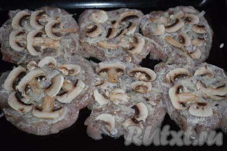 На отбивные с луком выкладываем нарезанные шампиньоны.