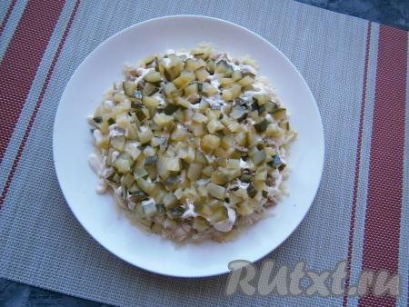 Следующим слоем выложить маринованный огурчик, нарезанный небольшими кубиками.