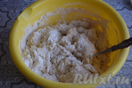 Начинаем замешивать тесто сначала при помощи ложки. Затем, когда тесто начнёт сворачиваться в ком, продолжаем замес руками.