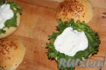 Листья салата вымыть и обсушить. Выложить на булочку лист салата и половину столовой ложки соуса.