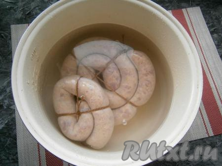 Колбасу проколоть иголкой в нескольких местах со всех сторон и поместить её в кастрюлю с холодной водой. Довести воду до кипения и варить домашнюю колбасу из курицы и свинины на самом слабом огне 30-40 минут. Я делала это в мультиварке на режиме "Варка на пару", выставив температуру 90 градусов и время - 1 час.