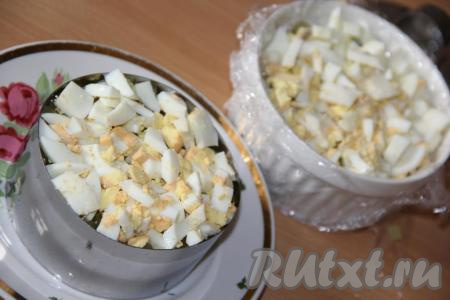 Мелко нарезать остывшие и очищенные варёные яйца, а затем выложить их поверх маринованного огурчика.