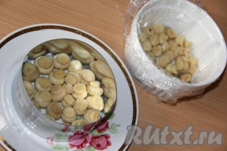 Куриное филе заранее отварить в подсоленной воде в течение минут 25-30 с начала кипения воды. Затем дать мясу остыть, не вынимая его из бульона. Отварить яйца в течение 10 минут с момента закипания воды. Для приготовления этого салата подойдут именно целенькие маринованные шампиньоны. Для того чтобы убрать лишний маринад, выложить грибы на дуршлаг и оставить на несколько минут. Формировать салат-перевёртыш "Грибная поляна" можно в кастрюльке (или другой удобной ёмкости), застеленной пищевой плёнкой, или с помощью бортиков для салата. На дно застеленной кастрюльки или формы выложить целые шампиньоны ножками вверх.