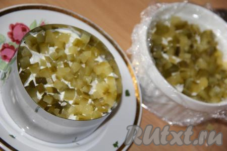 Нарезать маринованный огурец на кубики и выложить следующим слоем.