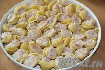 Каждую ракушку, отваренную до полуготовности, наполнить фаршем. Выложить ракушки с начинкой в форму для запекания (у меня большая форма диаметром 29 см).