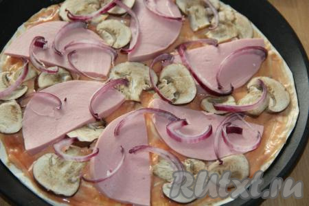 Лук нарезать тонкими полукольцами и выложить на колбасу и грибы.