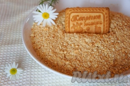 Прежде всего приготовим песочную основу чизкейка. Для этого нужно измельчить печенье. Я выкладываю печенье в целлофановый пакет, завязываю пакет и прокатываю скалкой поверх пакета до измельчения печенья в мелкую, однородную крошку.