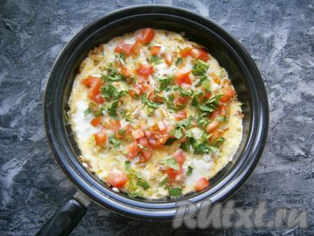 Сковородку прикрыть крышкой и на слабом огне готовить блюдо около 3-4 минут. Яйца должны схватиться, но остаться сверху немного жидкими. Помидор нарезать кубиками, зелень петрушки измельчить. Выложить помидоры сверху яиц и посыпать петрушкой, посолить и немного поперчить.