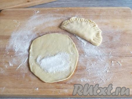 Ближе к краю раскатанной лепёшки выложите 1 чайную ложку сахара, распределите в пределах этого края (как на фото).