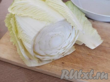 Подготовьте пекинскую капусту. Отрежьте основание кочана. Разберите листочки. Промойте их под проточной водой.